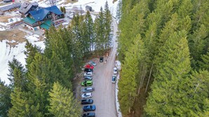 An aerial view of a forested area with a row of parked cars and a building with a blue roof.