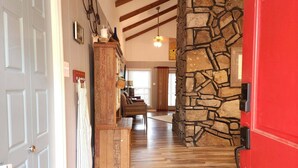 Un pasillo con pared de piedra, suelo de madera y una puerta roja.