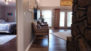 Una habitación con una cama, un sofá, una pared de piedra y un ventilador de techo.