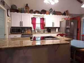 A kitchen with white cabinets, a stainless steel refrigerator, a microwave, and a sink.