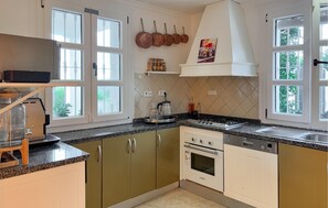 A kitchen with a stove, oven, dishwasher, and a window with a view of greenery. - Amazing home in Benahavis with private swimming pool, can be inside or outside (Benahavis)