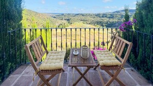 Un balcon avec deux chaises en bois et une table, offrant une vue sur un paysage magnifique.