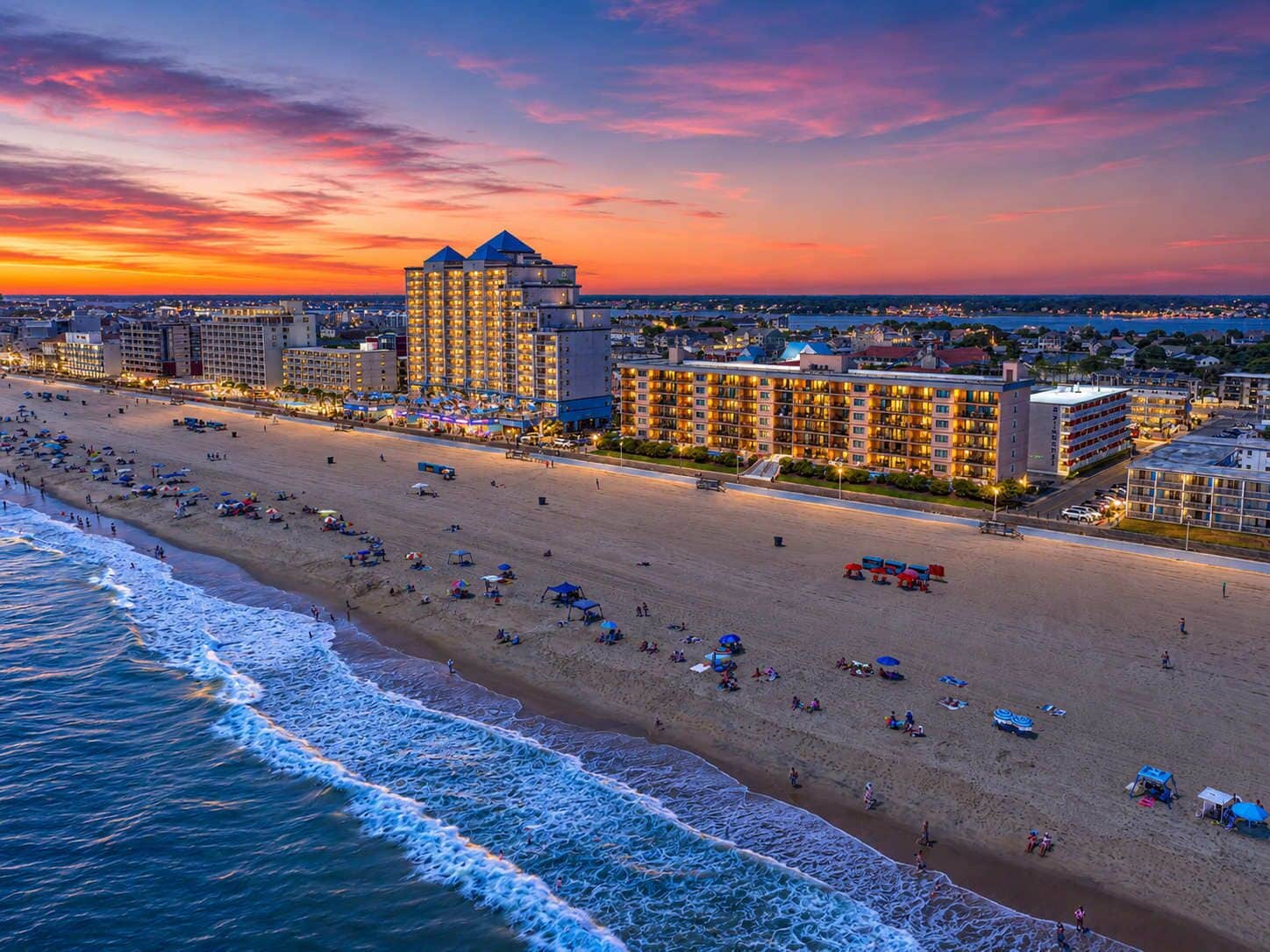 Un hotel frente a la playa con varias construcciones, una playa de arena y el océano.