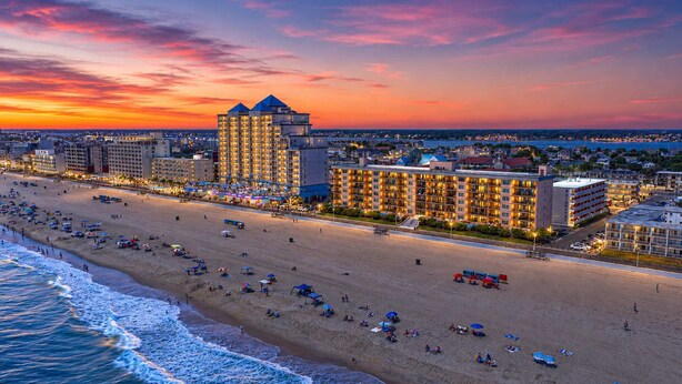 Un hotel frente a la playa con varias construcciones, una playa de arena y el océano.