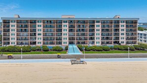Un hotel de varios pisos con una escalera central, balcones y vista a la playa.