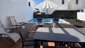 A poolside area with a pergola, lounge chairs, a table, and a pool. - Papagayo House, Playa Blanca (Playa Blanca)
