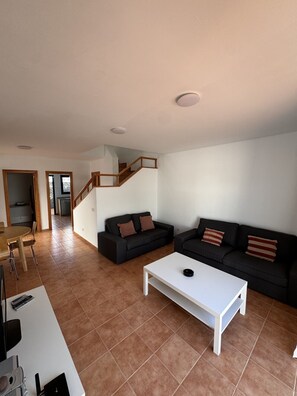 A spacious living area with a staircase, two black sofas with striped pillows, a white coffee table, and a dining area with chairs. - Papagayo House, Playa Blanca (Playa Blanca)