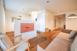 Un moderno vestíbulo de hotel con televisión de pantalla plana, sofás, una mesa de centro y piso de madera.
