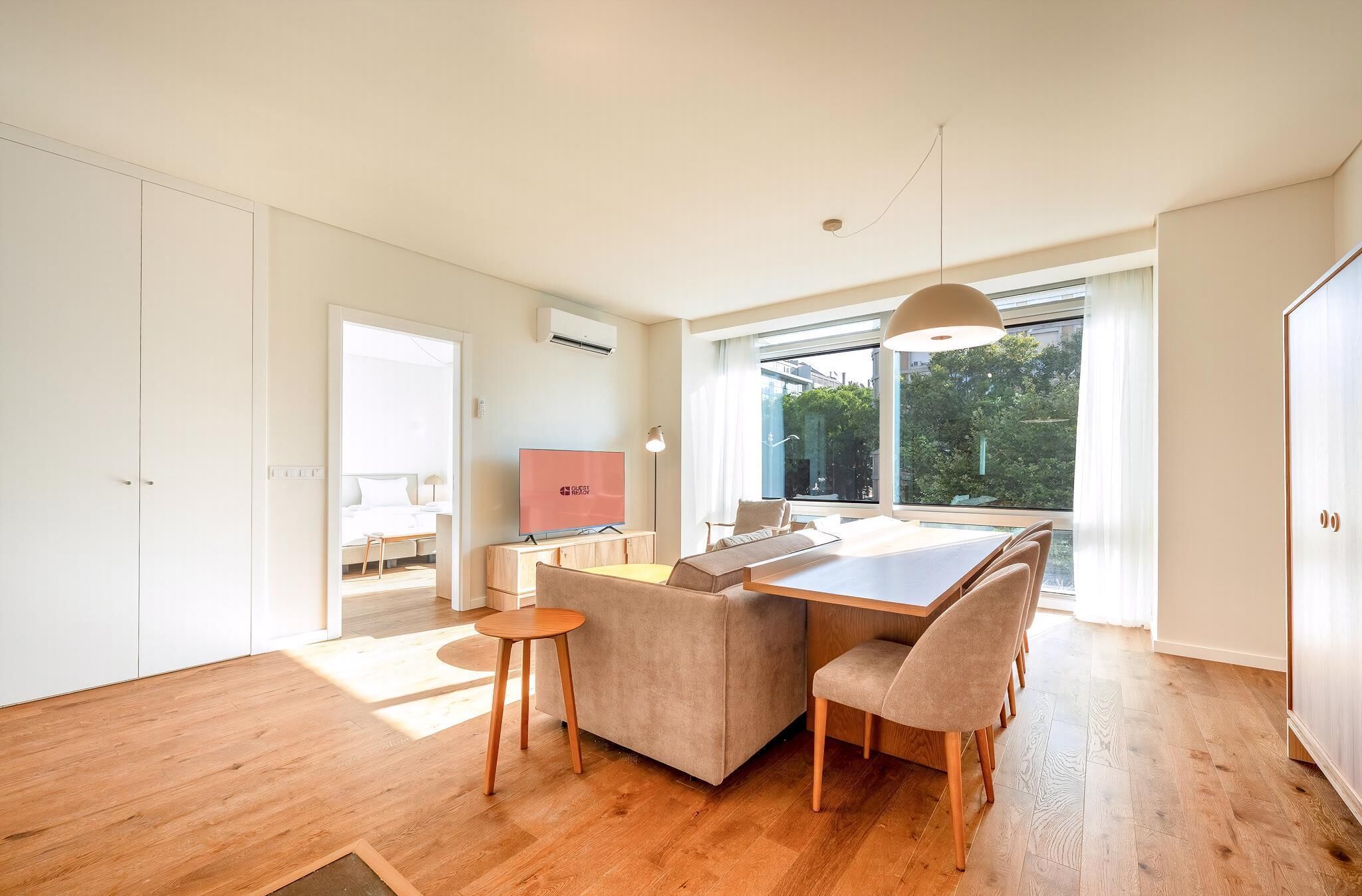 A modern kitchen with a dining area, wooden flooring, and large windows.