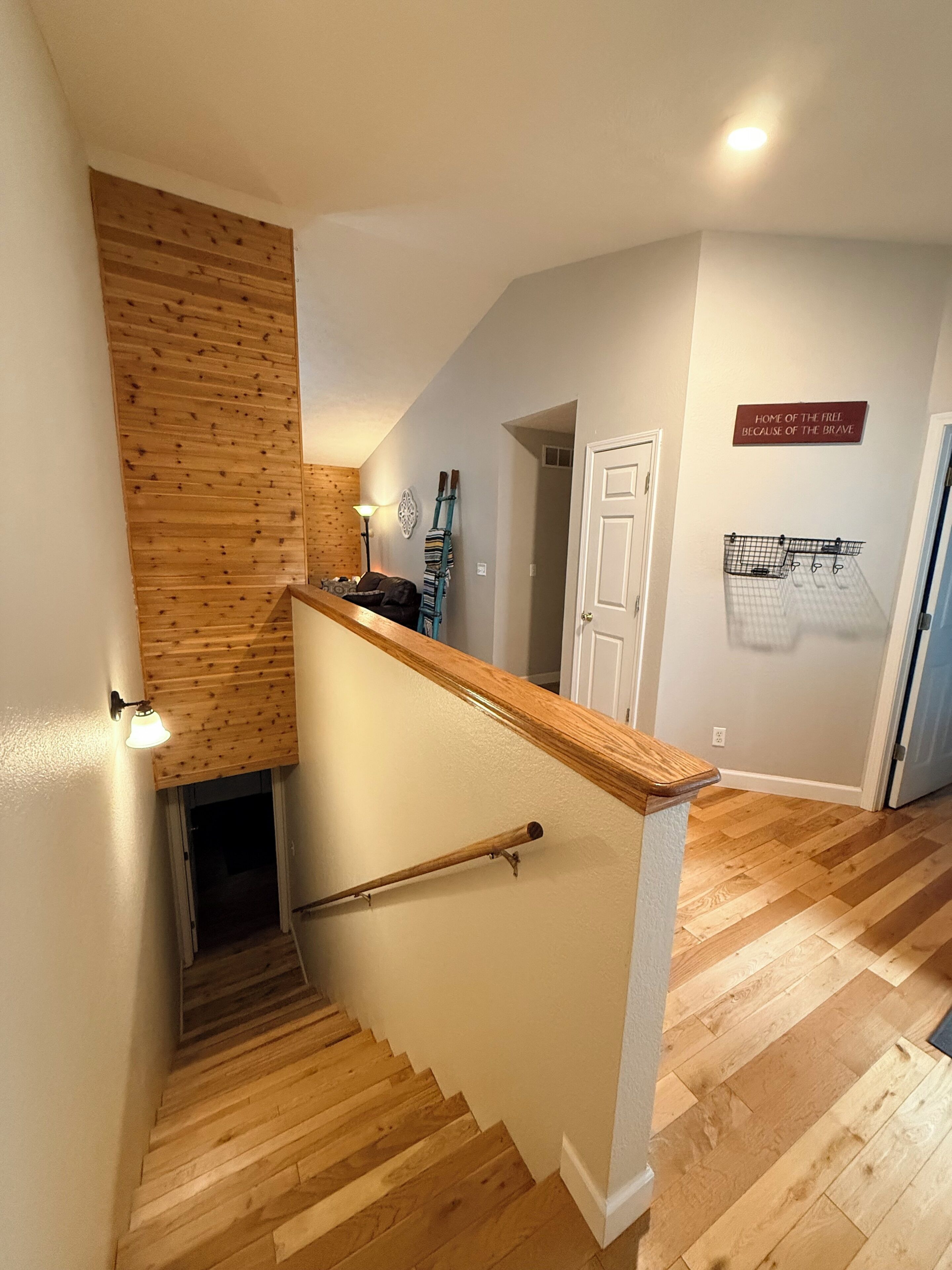 A wooden staircase with a handrail, a wall-mounted light, and a door.