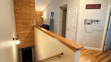 A wooden staircase with a handrail, a wall-mounted light, and a door.