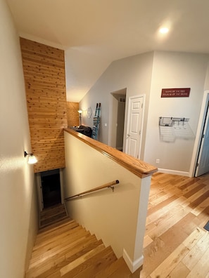 A wooden staircase with a handrail, a wall-mounted light, and a door.