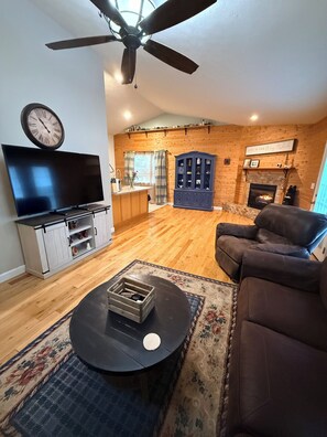 Ein Wohnzimmer mit Fernseher, Sofa, Couchtisch und Kamin.
