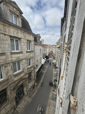 Eine schmale Straße, gesäumt von historischen Gebäuden aus Stein mit sichtbaren Fenstern und Türen, einige Fußgänger und abgestellte Fahrräder.
