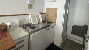 Une cuisine de taille réduite, équipée d’un évier, d’une cuisinière et de placards de rangement.