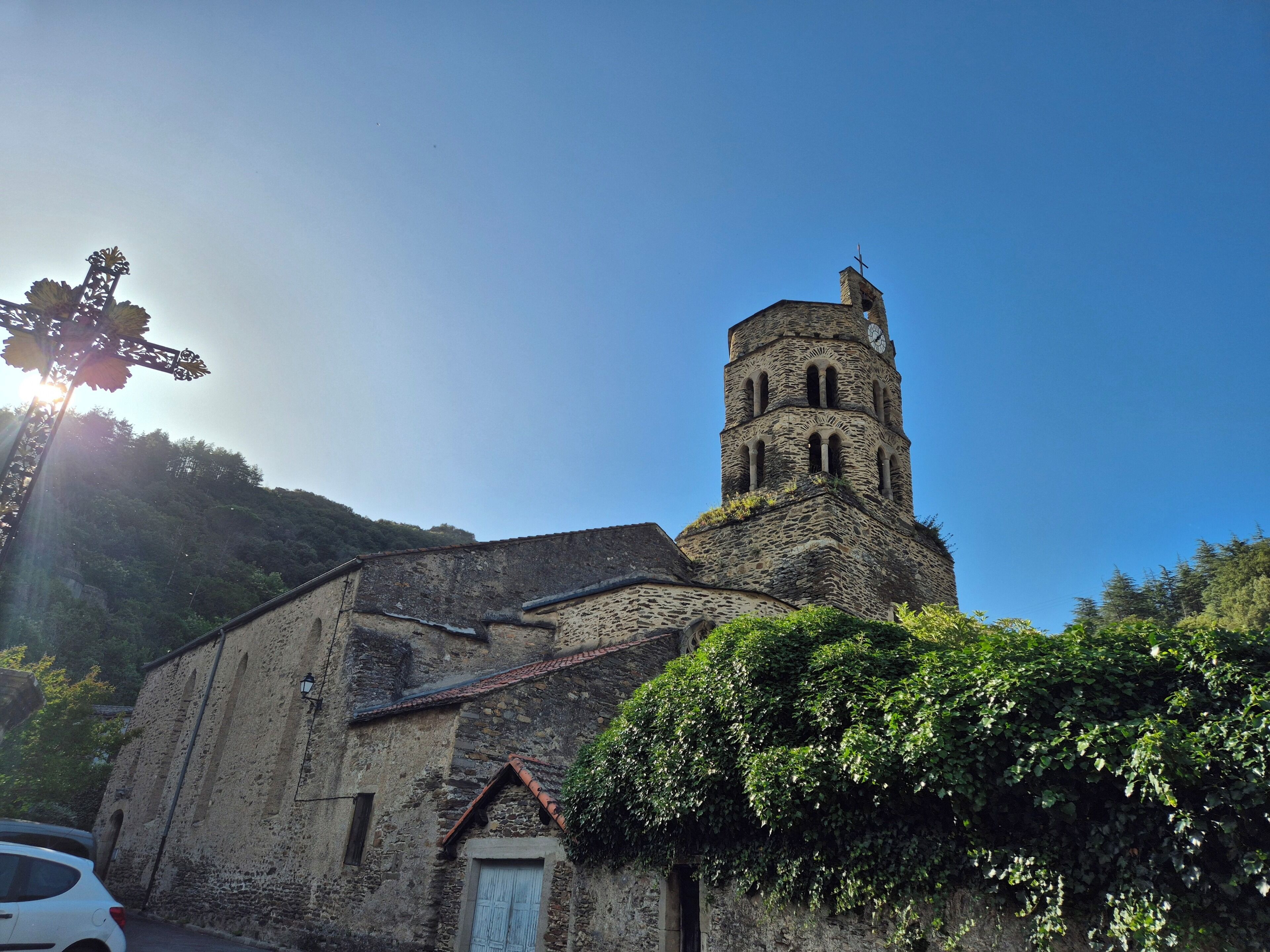 Una iglesia con un campanario, muros de piedra y una cruz.