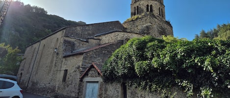 Una iglesia con un campanario, muros de piedra y una cruz.