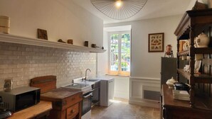 A kitchen with a brick wall, a window, and a wooden cabinet.