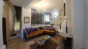 A living room with a sofa, a glass coffee table, a fireplace, and a chandelier.
