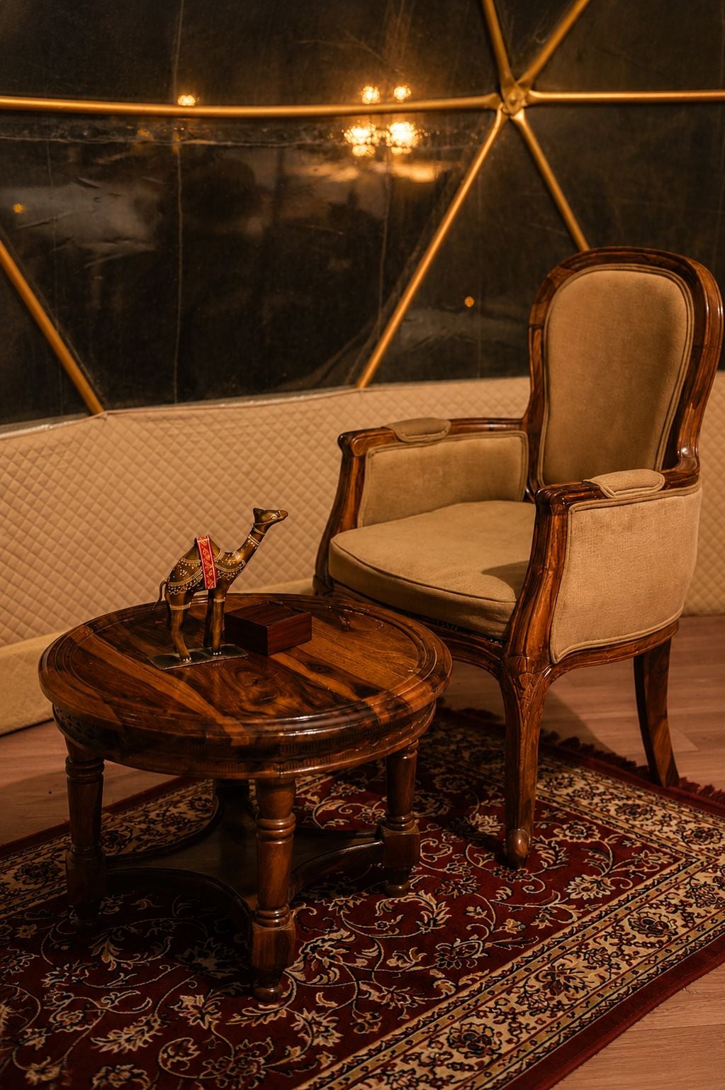 A room with a round wooden table, a cushioned chair, and a patterned rug.