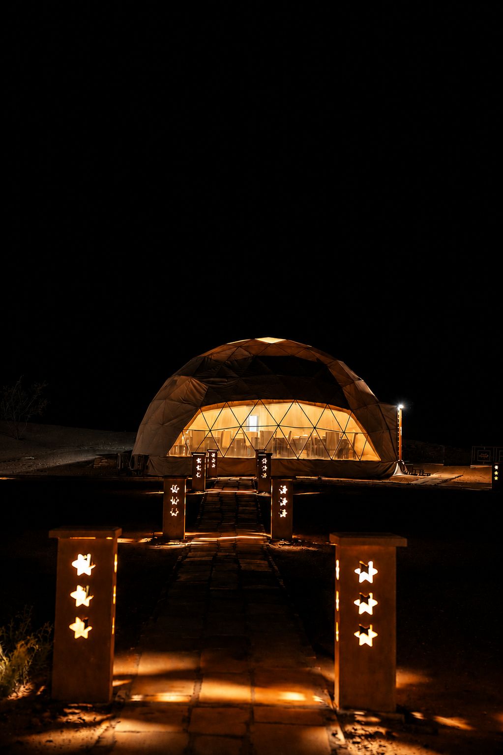 A dome-shaped structure with a central light source, a pathway leading to it, and star-shaped decorations on the pathway.