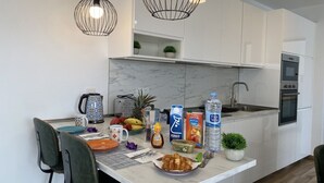 A modern kitchen with white cabinetry, a marble countertop, and a dining area with chairs and a table set for breakfast. - Casa Aday, Playa Blanca (Playa Blanca)