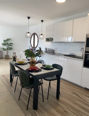 A modern kitchen with white cabinets, a dining table with chairs, pendant lights, and a potted plant. - Casa Aday, Playa Blanca (Playa Blanca)