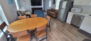 A modern kitchen with a dining table, chairs, a refrigerator, microwave, and a dishwasher.