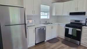 A modern kitchen with stainless steel appliances, white cabinetry, a dishwasher, and a coffee maker.