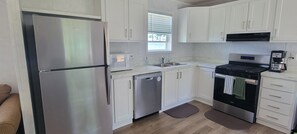 A modern kitchen with stainless steel appliances, white cabinetry, a dishwasher, and a coffee maker.