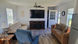 A living room with a sofa, armchair, TV, and a ceiling fan.