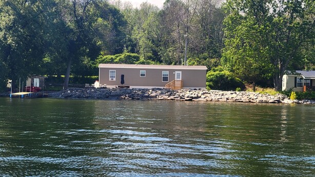 A lakeside cabin with a dock, surrounded by trees.
