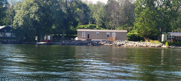 Una cabaña junto al lago con un muelle, rodeada de árboles.