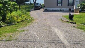 A gravel driveway leading to a house with a lawn and a parked truck.