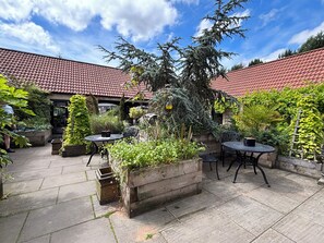 A courtyard with a tiled roof, outdoor seating, and various plants. - Kingfisher Hut (Sheffield)
