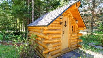 A log cabin with a door and windows, surrounded by a forest.