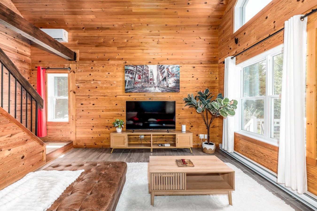 Una sala de estar acogedora con interiores de madera, un televisor de pantalla plana, un sofá cómodo y un ventanal amplio.