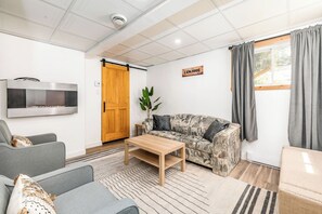 Uma sala de estar moderna com um sofá, uma mesa de centro, uma televisão e uma porta deslizante.