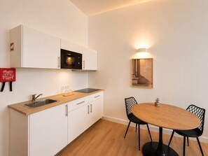 Eine moderne Küche mit weißen Schränken, einer schwarzen Mikrowelle, einem Spülbecken und einem Holzespeisetisch mit schwarzen Stühlen.