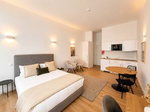A modern hotel room with a large bed, a small desk, a dining table, and a kitchenette. - Porto Ribeira Hotel - Studio (Porto)