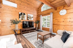 A wooden interior with a TV, sofa, and a clock. - Le Floréa / Private Spa / BBQ & Garden / Games, Nature & Relax (Shannon)