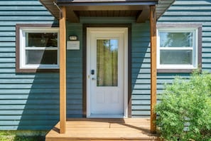 A house with a front door, two windows, and a wooden porch.