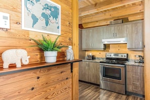 A kitchen with wooden cabinets, a stove, a toaster, and a potted plant.