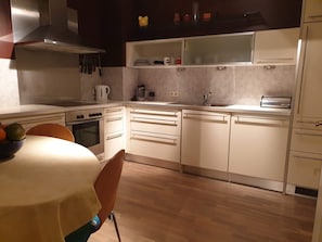 A modern kitchen with white cabinetry, a built-in oven, and a stainless steel range hood. - Apartment Sleeps 6 With Garden & Balcony (Vienna)