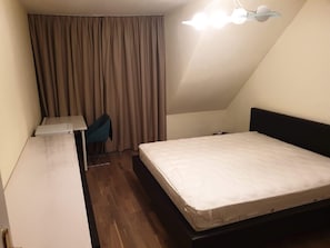 A small, single-room hotel room with a bed, a desk, a chair, and a ceiling light. - Apartment Sleeps 6 With Garden & Balcony (Vienna)