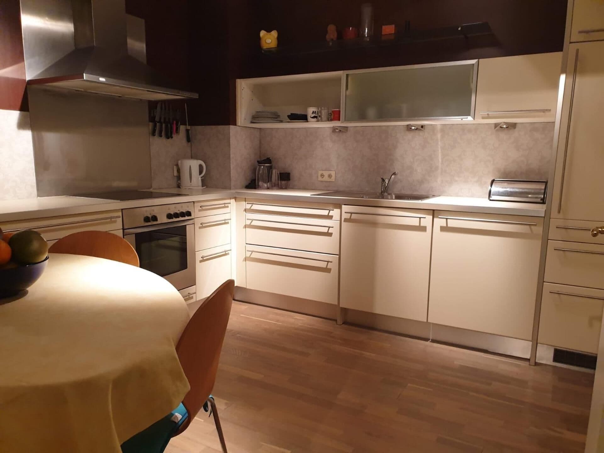 A modern kitchen with white cabinetry, a stove, oven, and a dining area with a table and chairs.