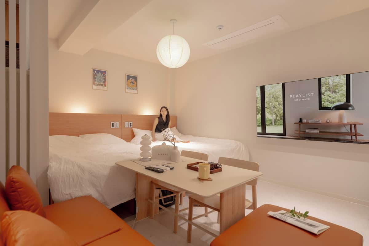 Una habitación de hotel moderna con dos camas, una mesa de comedor y un ventanal con vistas.