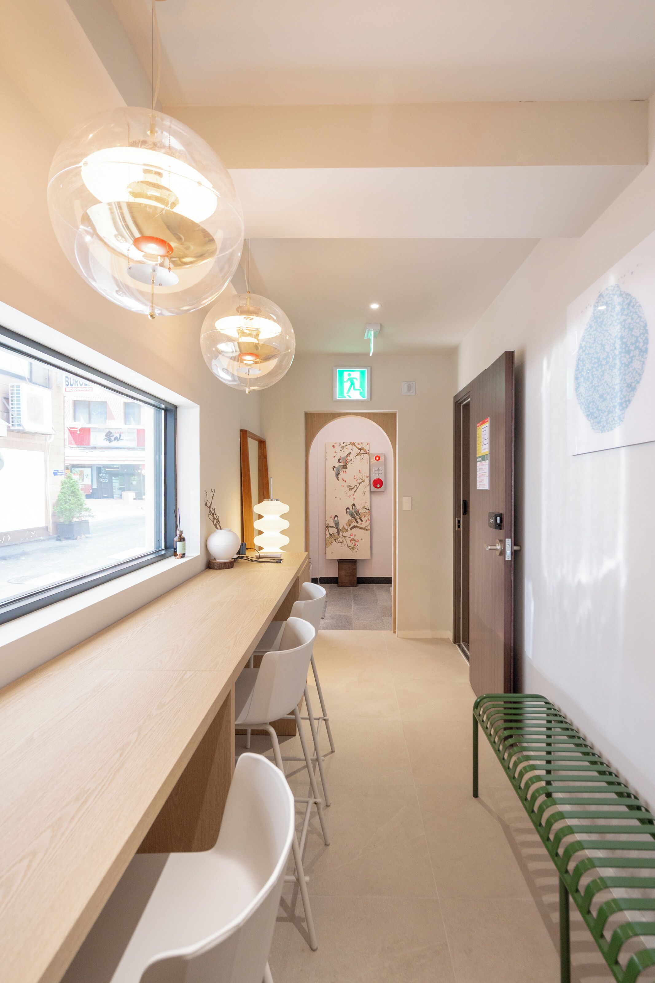 A reception area with a wooden desk, white chairs, a green bench, and pendant lights.