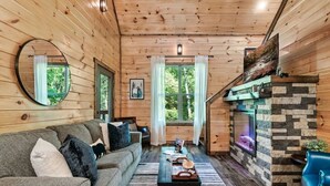 L’intérieur chaleureux d’un chalet, avec un décor en bois, un canapé, une table et une cheminée.