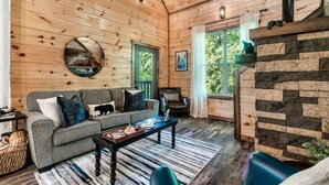 Un intérieur de chalet chaleureux avec un canapé, un fauteuil, une table basse et une cheminée.